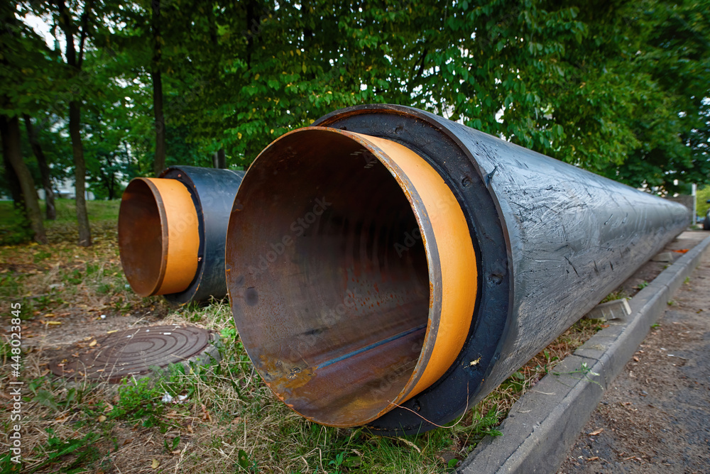 Stack of insulated pipes for pipeline, underground heat system. Water pipes with insulation lie on the ground. Water main replacement. Heating system pipelines - replacement and reconstruction Stack of insulated pipes for pipeline, underground heat system. Water pipes with insulation lie on the ground. Water main replacement. Heating system pipelines - replacement and reconstruction
