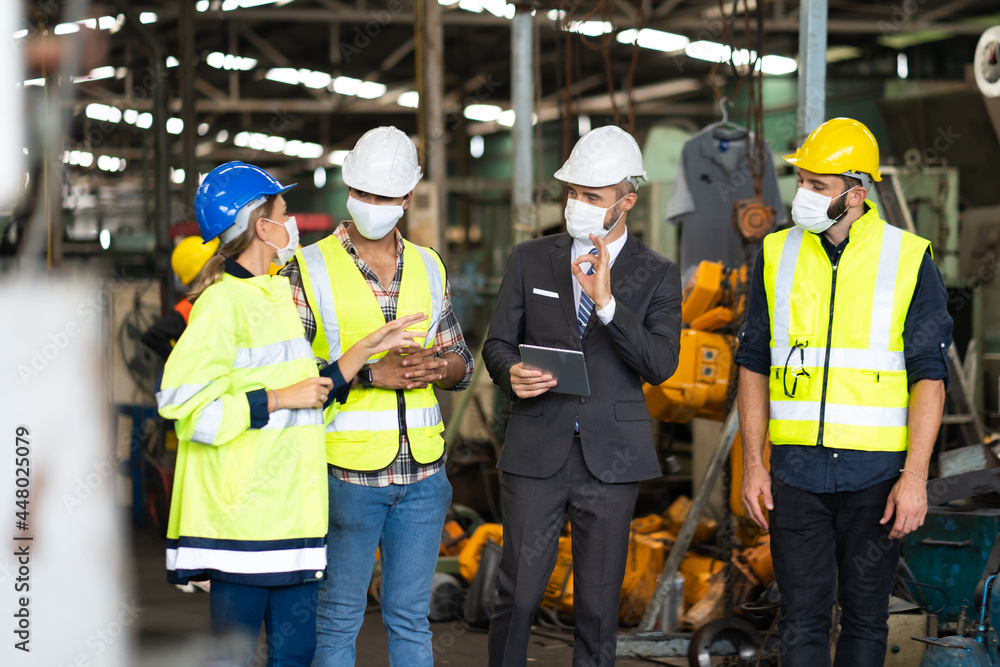 Engineers people are brainstorming solving problems of heavy industrial machinery. Worker man and asian woman wearing face mask prevent covid-19 virus and protective hard hat. . Engineers people are brainstorming solving problems of heavy industrial machinery. Worker man and asian woman wearing face mask prevent covid-19 virus and protective hard hat. .