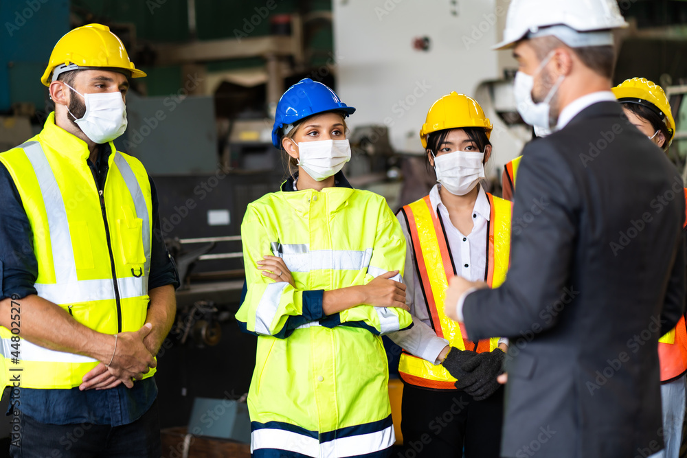 Group of engineers Workers wear protective face masks for safety in machine industrial factory. Worker man wearing face mask prevent covid-19 virus and protective hard hat. Group of engineers Workers wear protective face masks for safety in machine industrial factory. Worker man wearing face mask prevent covid-19 virus and protective hard hat.