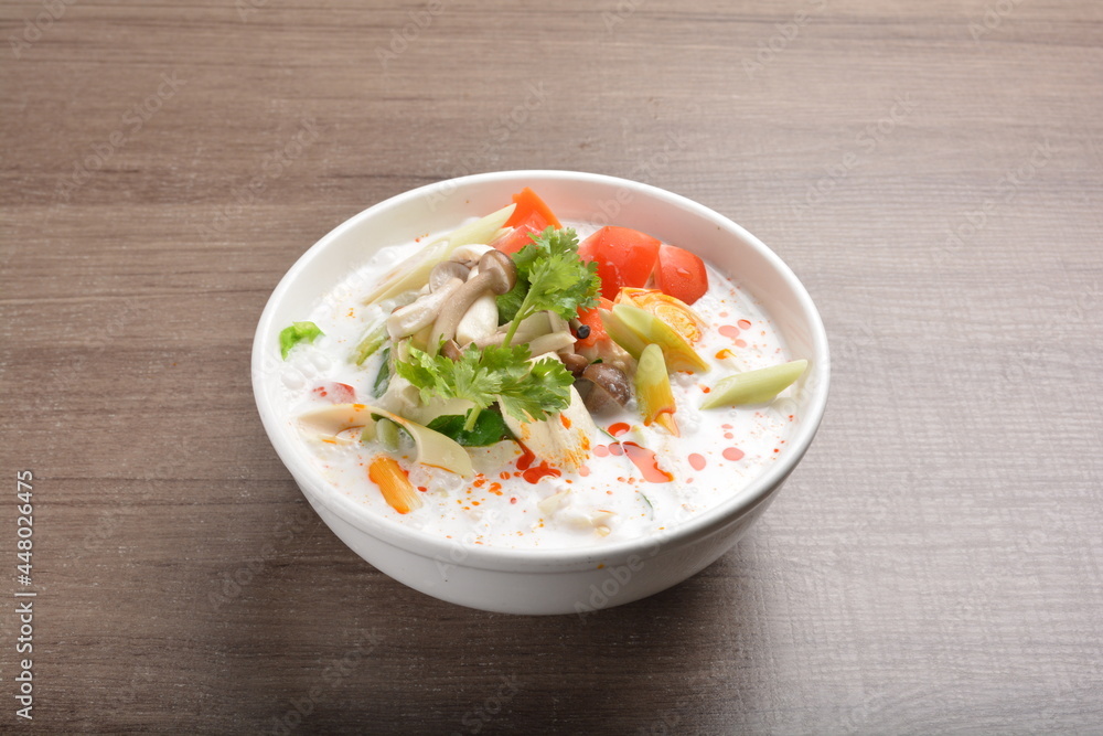cook hot and spicy white coconut curry laksa soup with mushroom and mixed vegetables in white bowl on wood background asian halal vegan menu cook hot and spicy white coconut curry laksa soup with mushroom and mixed vegetables in white bowl on wood background asian halal vegan menu