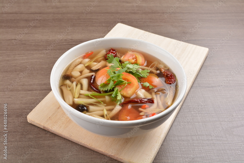 cook hot and spicy tom yum soup with mushroom and mixed vegetables in white bowl on wood background asian halal vegan menu