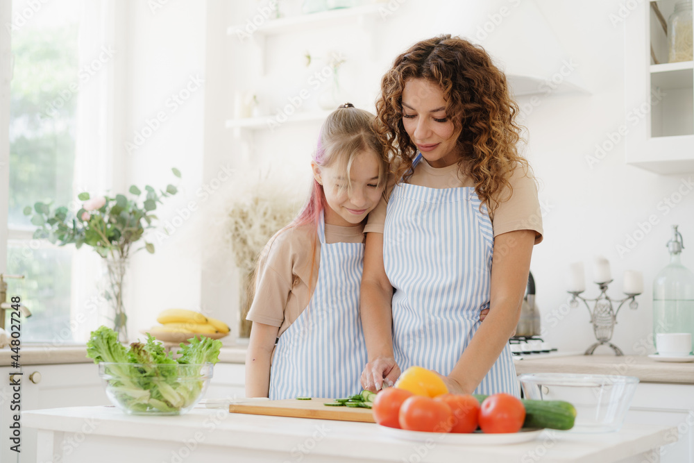 Mother and teen daughter preparing vegetable salad at kitchen Mother and teen daughter preparing vegetable salad at kitchen