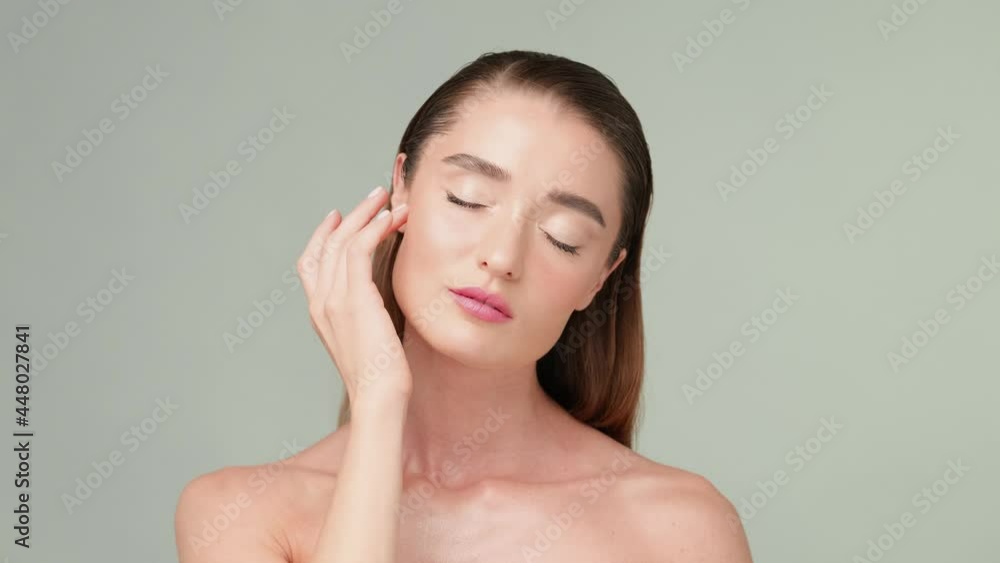 Beautiful Young Woman with Clean Fresh Skin standing over light grey background Beautiful Young Woman with Clean Fresh Skin standing over light grey background