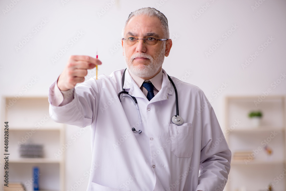 Old male doctor in vaccination concept