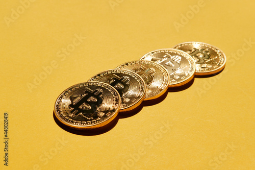Crypto currency Bitcoin physical coin on yellow background.