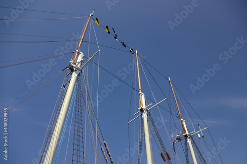 Close up view of wooden masts with signal flags on a clear blue sky background. Marine festival of tall ships - Sail Tallinn 2021. July, Estonia, Europe