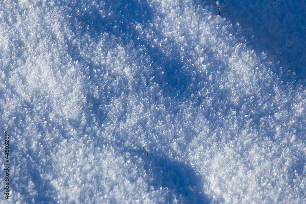 Fresh white snow sparkling in the sun with highlights and shadows for background