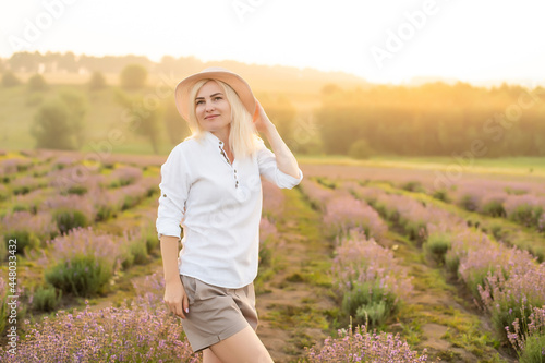 Young woman standing on a lavender field with sunrise on the background