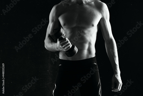 sporty man with dumbbells in hands pumping up muscles exercises dark background
