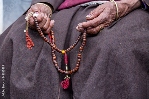 Old Tibetan woman holding buddhist rosary in Hemis monastery, Ladakh, India. Hand and rosary