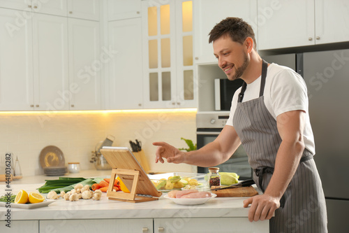 Man watching online cooking course via tablet in kitchen