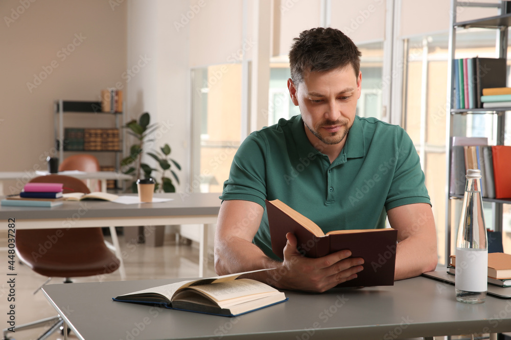 Man reading book at table in library Man reading book at table in library