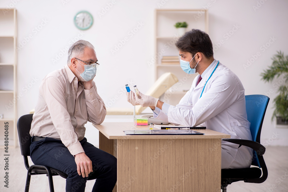 Old male patient visiting young male doctor in vaccination conce Old male patient visiting young male doctor in vaccination conce