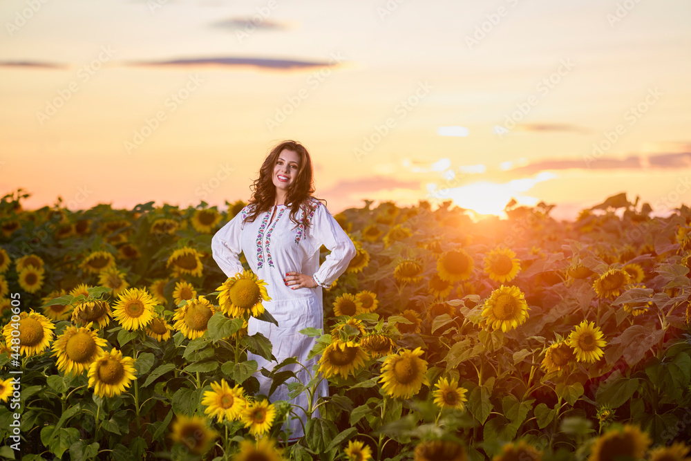 Beautiful woman enjoying nature in the sunflower field at sunset. Traditional clothes. Attractive brunette woman with long and healthy hair. Beautiful woman enjoying nature in the sunflower field at sunset. Traditional clothes. Attractive brunette woman with long and healthy hair.