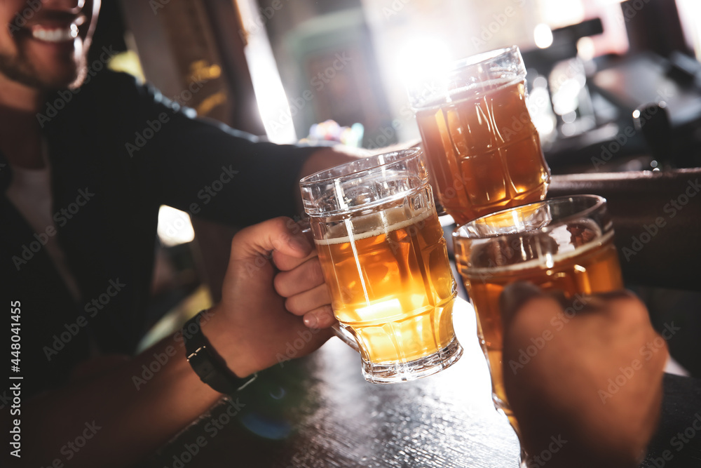 Friends clinking glasses with beer in pub, closeup