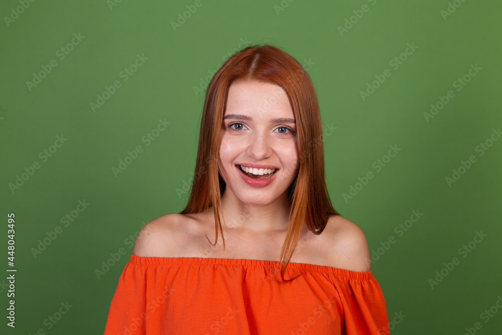 Young red hair woman in casual orange blouse on green background look to camera excited smile laugh Young red hair woman in casual orange blouse on green background look to camera excited smile laugh