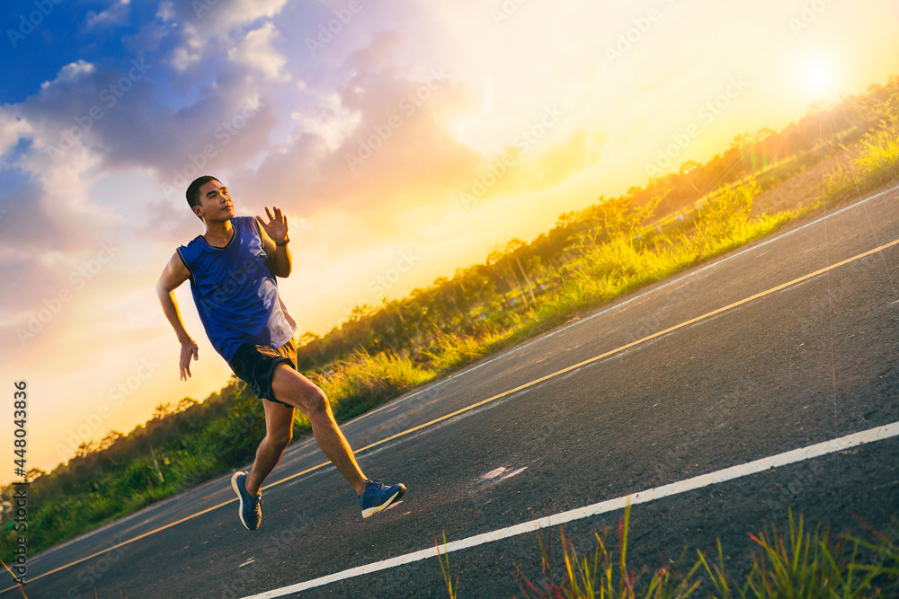 Silhouette of Young man running sprinting on road. Fit runner fitness runner during outdoor workout with sunset background. Selected focus.