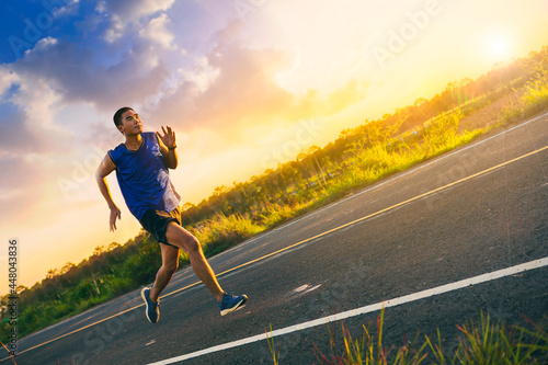 Silhouette of Young man running sprinting on road. Fit runner fitness runner during outdoor workout with sunset background. Selected focus.