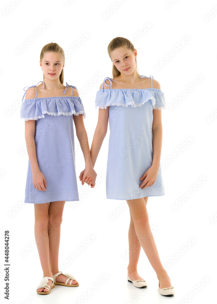 Sisters in Identical Light Dresses Standing and Holding Hands Sisters in Identical Light Dresses Standing and Holding Hands