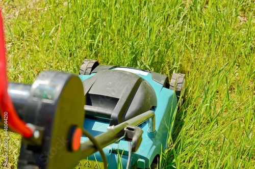 Electric lawn mower while mowing a grass and lawn. Garden lawn mowing, professional care service and maintenance.