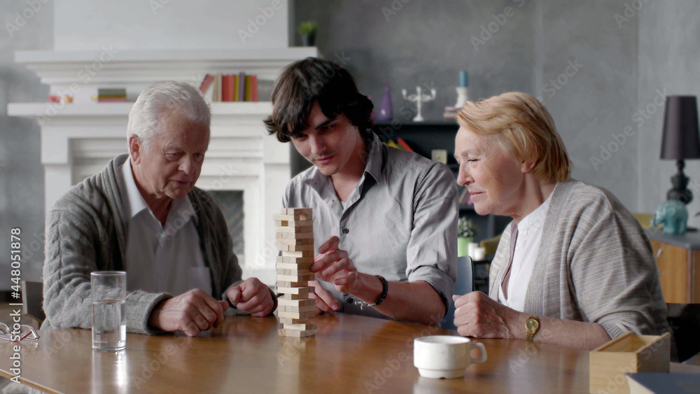 Fototapeta premium Happy grandparents and young grandson play board game at home