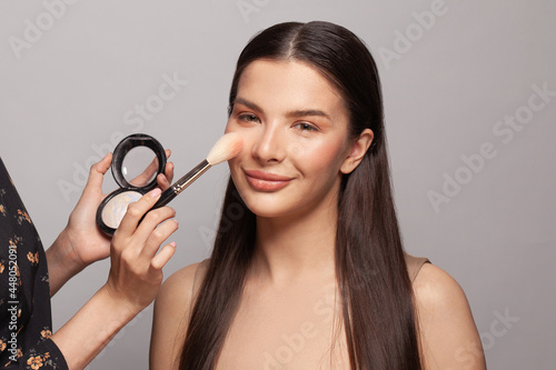 Makeup concept. Close up make-up artist hands applying powder and highlighter on client skin