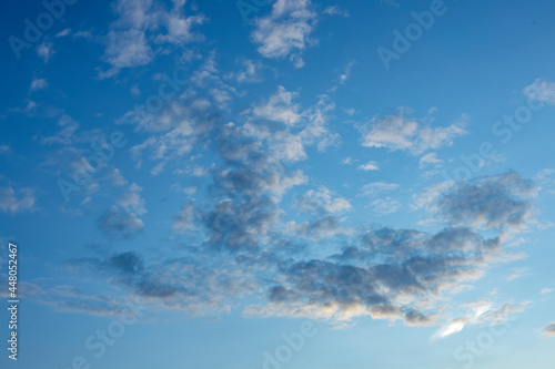 Fototapeta Naklejka Na Ścianę i Meble -  Sunset soft tones enlighten a flock of small cumulus clouds contrasting against a blue vibrant sky. Weather conditions and climate concept. Abstract background wallpaper poster.