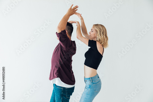 a man and a woman dance bachata to music in a white room photo