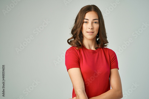 cheerful woman in red t-shirt holding hair isolated background posing