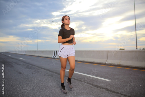 Young fitness Asian woman wear a black shirt and white shorts. is running and jogging an outdoor workout on the city road in the for lifestyle health.