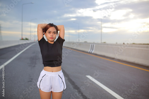 Young fitness Asian woman wear a black shirt and white shorts. is stretching in and jogging an outdoor workout on the city road in the for lifestyle health.