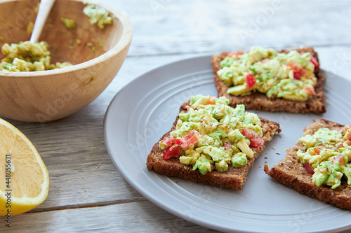 Vegetarian green sandwiches with avocado and tomatoes chopped on wooden grey table