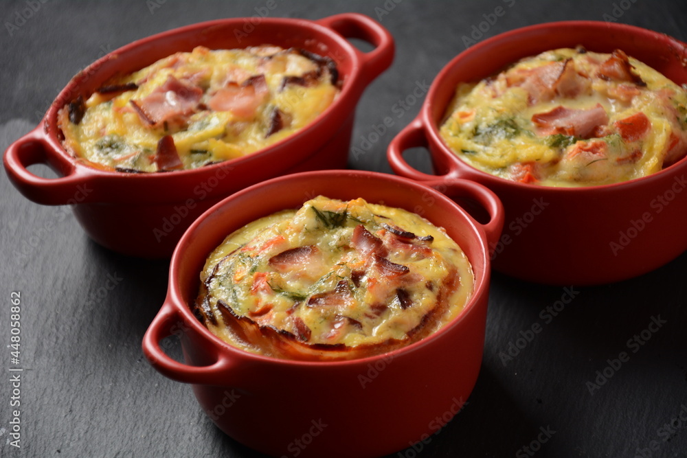 Omelette with bacon, grated parmesan and greens in ceramic cocotte. Tasty breakfast Omelette with bacon, grated parmesan and greens in ceramic cocotte. Tasty breakfast