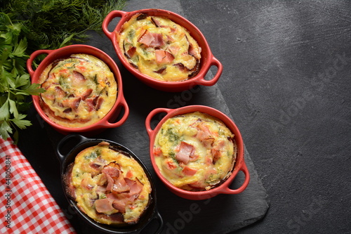 Omelette with bacon, grated parmesan and greens in ceramic cocotte. Tasty breakfast