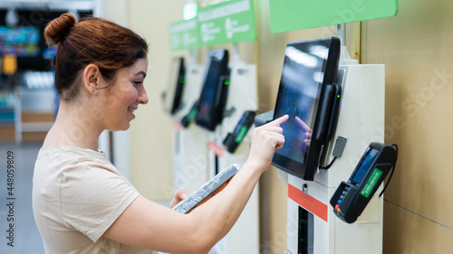 Fotografie Caucasian woman uses a self-checkout counter