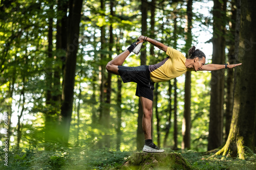 Junger Mann mit dunkler Haut macht Yoga Übung im Wald in der Natur