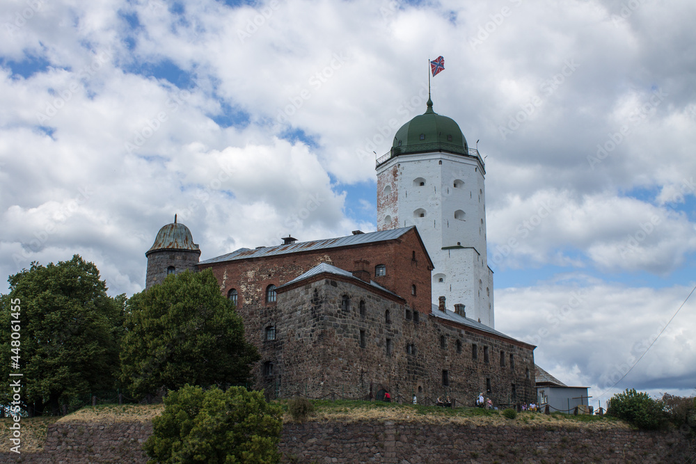 VYBORG, Leningrad REGION, RUSSIA-JULY, 19, 2021: the facade of a medieval fortress with a white Olaf tower surrounded by water on a cloudy summer day in the old town