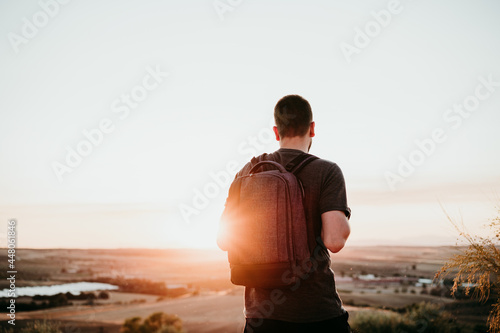 back view of relaxed hiker man with backpack at sunset in mountain. Hiking and nature