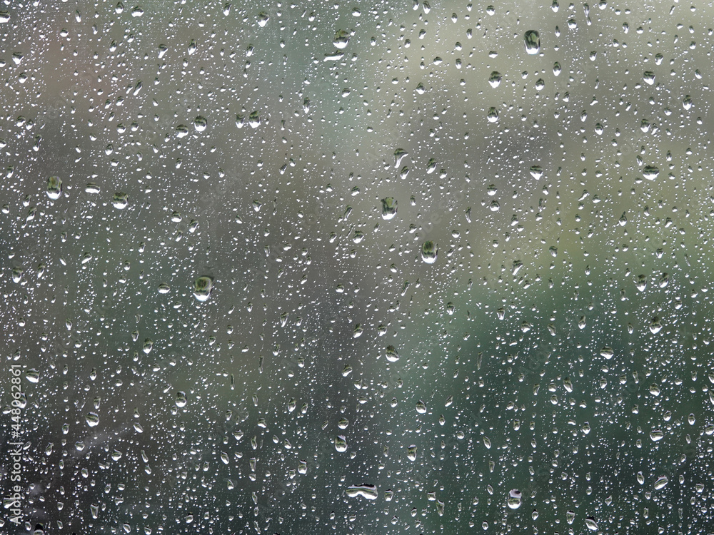 Background of glass covered with falling drops of heavy rain.