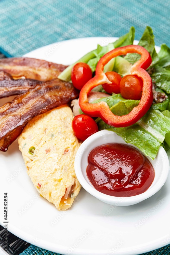 Western breakfast, scrambled eggs, bacon and fresh vegetables with tomato sauce Western breakfast, scrambled eggs, bacon and fresh vegetables with tomato sauce