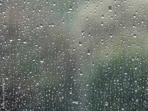 Background of glass covered with falling drops of heavy rain.