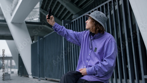 Stylish hipster taking selfie on smartphone. Focused man posing on phone camera.