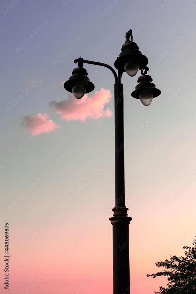 Silhouettes of three lanterns on a pole against a background of pink clouds. Concept for text or book cover. Vertical banner.