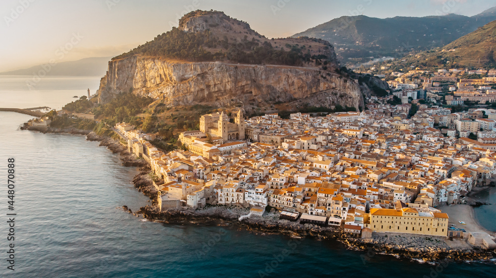 Sunrise over harbor in Cefalu, Sicily, Italy, panoramic aerial view of old town with colorful waterfront houses, sea and La Rocca cliff.Attractive summer cityscape,travel holiday concept background.