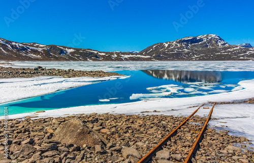 Old rails lead into water of frozen lake Vavatn Hemsedal. photo