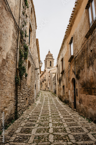 Narrow street in Erice with San Martino church tower Sicily Italy.Historical center of Italian village. Amazing medieval Mediterranean stone buildings and houses. Popular tourist destination