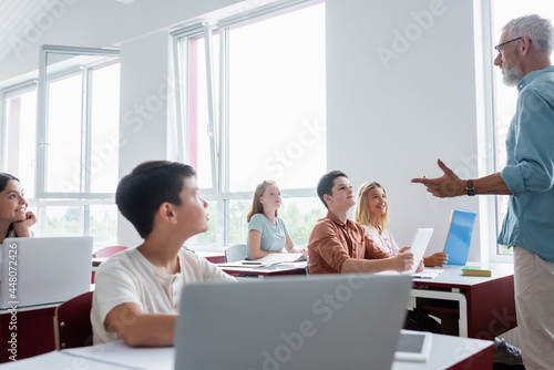 multicultural teenage pupils listening to middle aged teacher talking during lesson