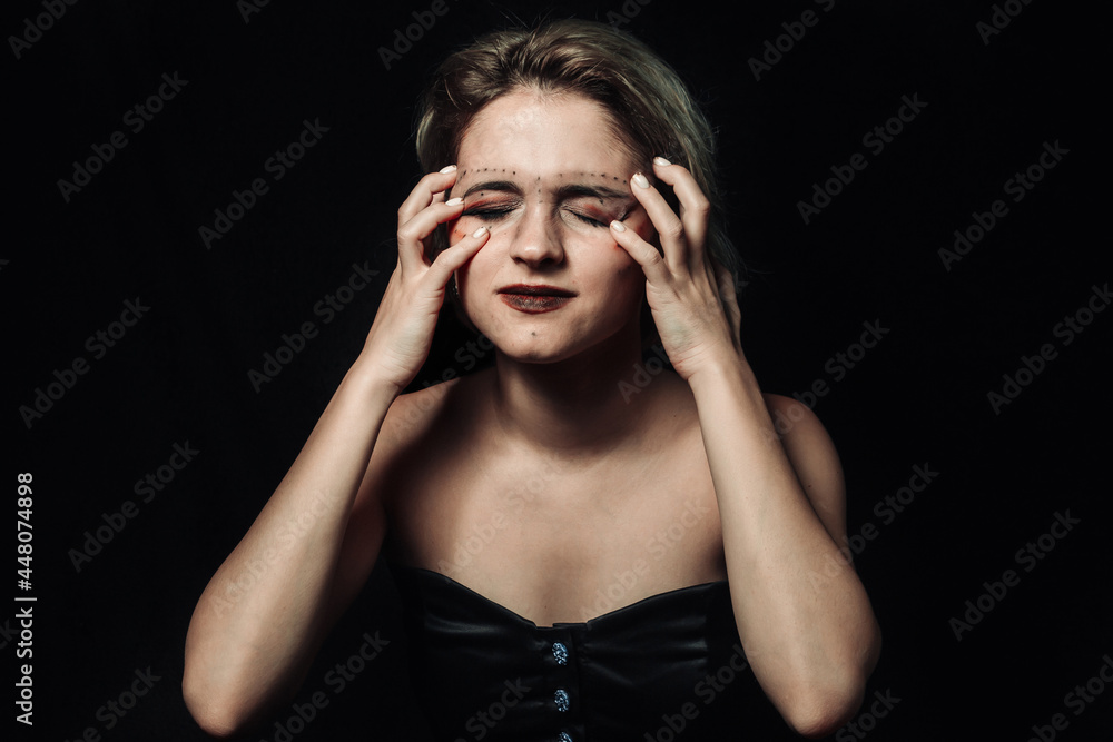 Female on a black background. Girl with smeared makeup. Girl holding her head with her hands in pain Female on a black background. Girl with smeared makeup. Girl holding her head with her hands in pain