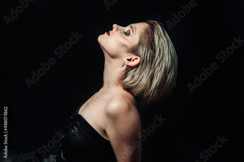 Female portrait in profile on a black background. Girl with makeup on a dark background