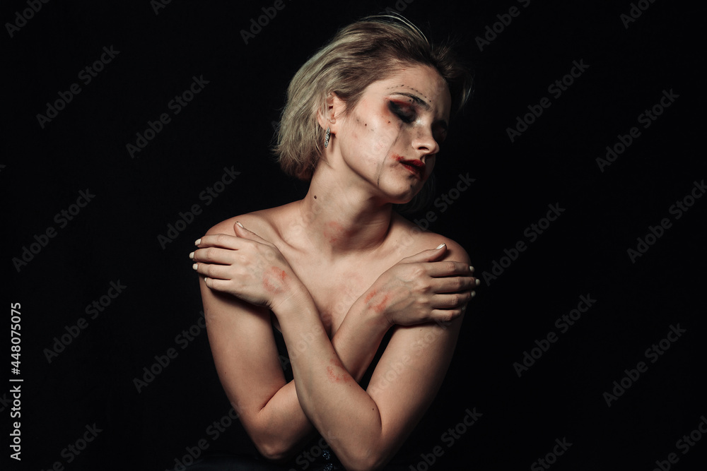 Portrait of a girl on a black background. A girl with smeared makeup hugs herself. Portrait of a girl on a black background. A girl with smeared makeup hugs herself.